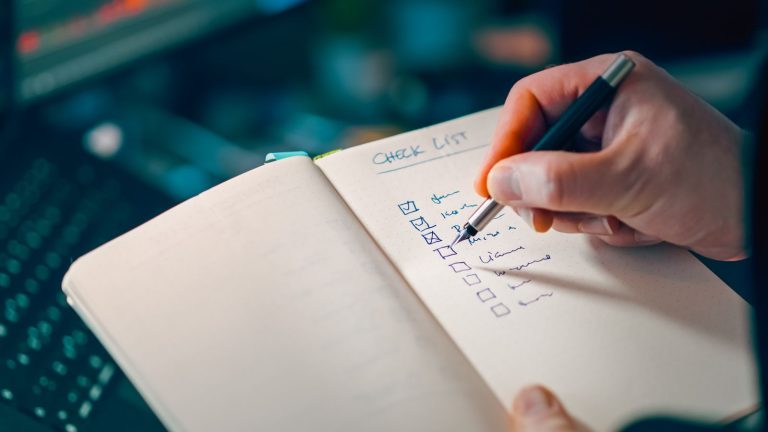 Hand writing a checklist in a notebook for visa application steps