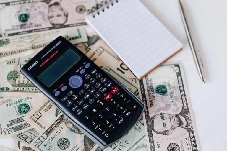 Electronic calculator and notepad placed over US dollar bills