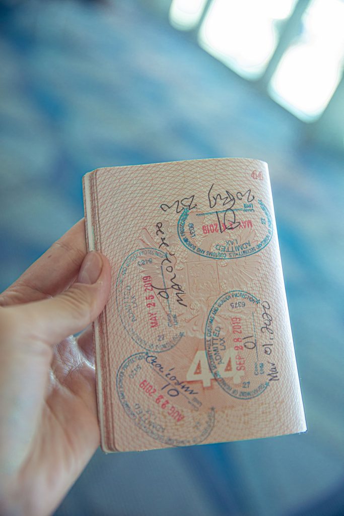 Hand holding an open passport showing renewal and extension stamps