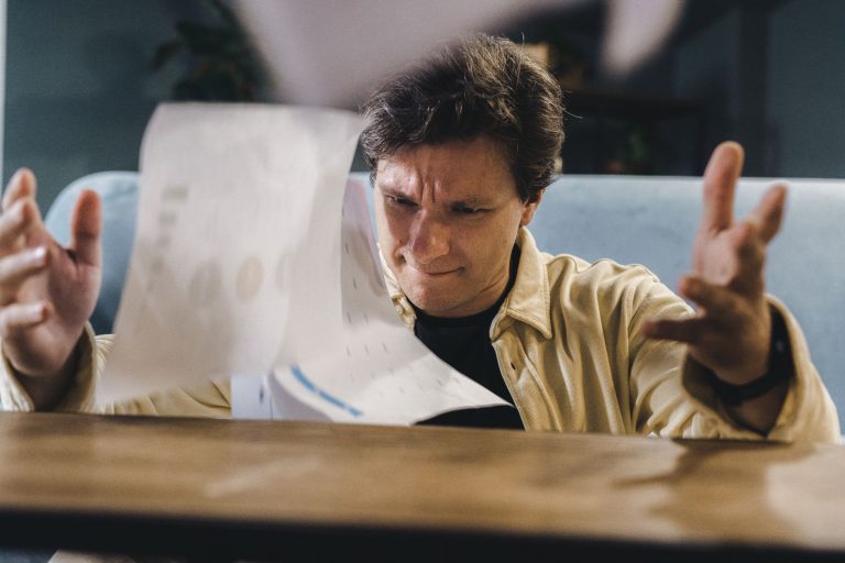 Stressed man frustrated with visa application paperwork at his desk