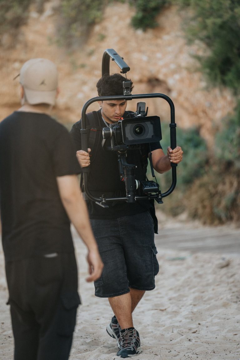 Professional cameraman operating a stabilizer on a sandy beach