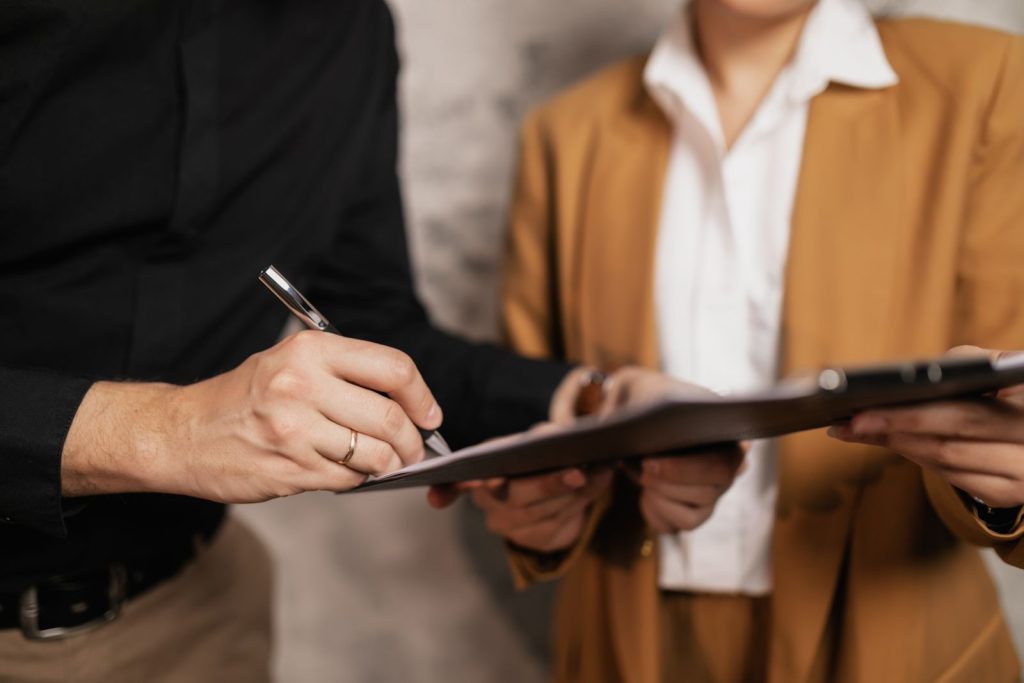 Close-up of two professionals signing a guarantor document