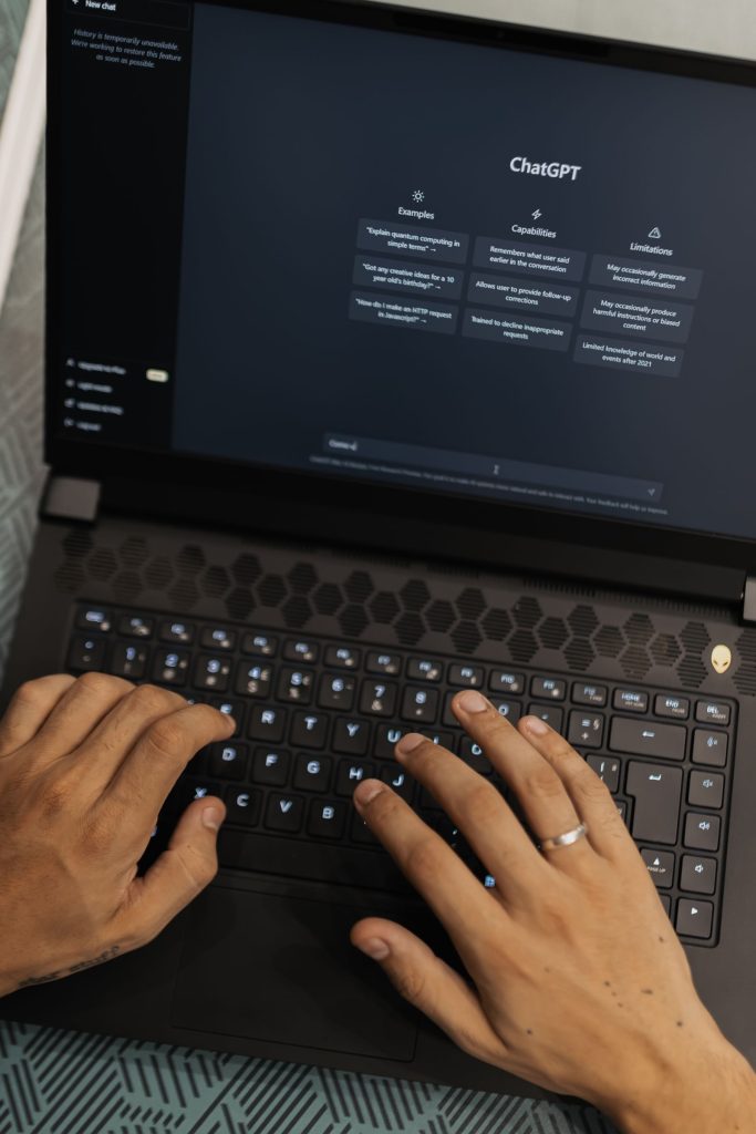 Hands typing on laptop showing ChatGPT AI assistant interface