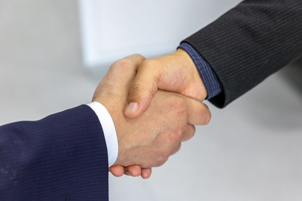 Close-up of two businessmen shaking hands symbolizing a sponsorship agreement