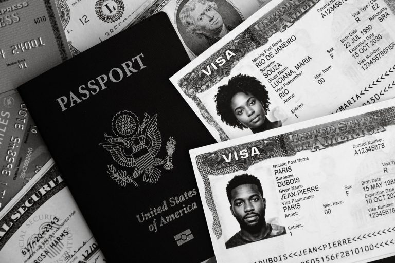 Monochrome close-up of a passport with visa stamps and currency for comparison