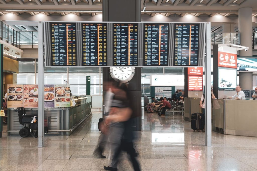 Blurred travelers rushing past an airport departure board and clock